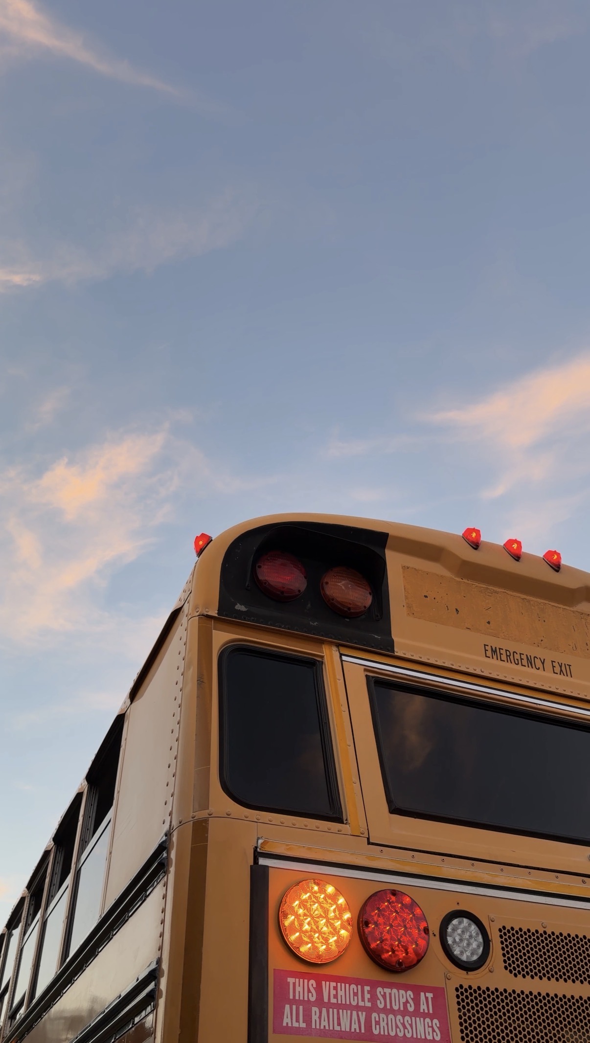 Rear corner detail of the bus with lights illuminated at sunset